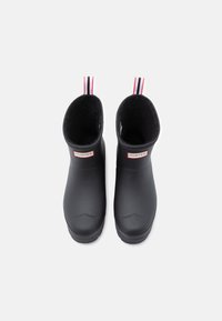 Bottes de cheville en caoutchouc noir avec une finition lisse, dotées d'une doublure confortable et de poignées rayées en rouge, blanc et bleu au sommet.