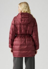 Chaqueta acolchada burdeos con capucha, que presenta una cintura ajustada, textura acolchada y diseño de longitud media. Tejido liso y brillante.