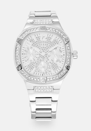 Montre-bracelet Guess argentée avec lunette en cristal et accents sur le bracelet, trois sous-cadrans affichant les fonctions 24 heures, jour et date.