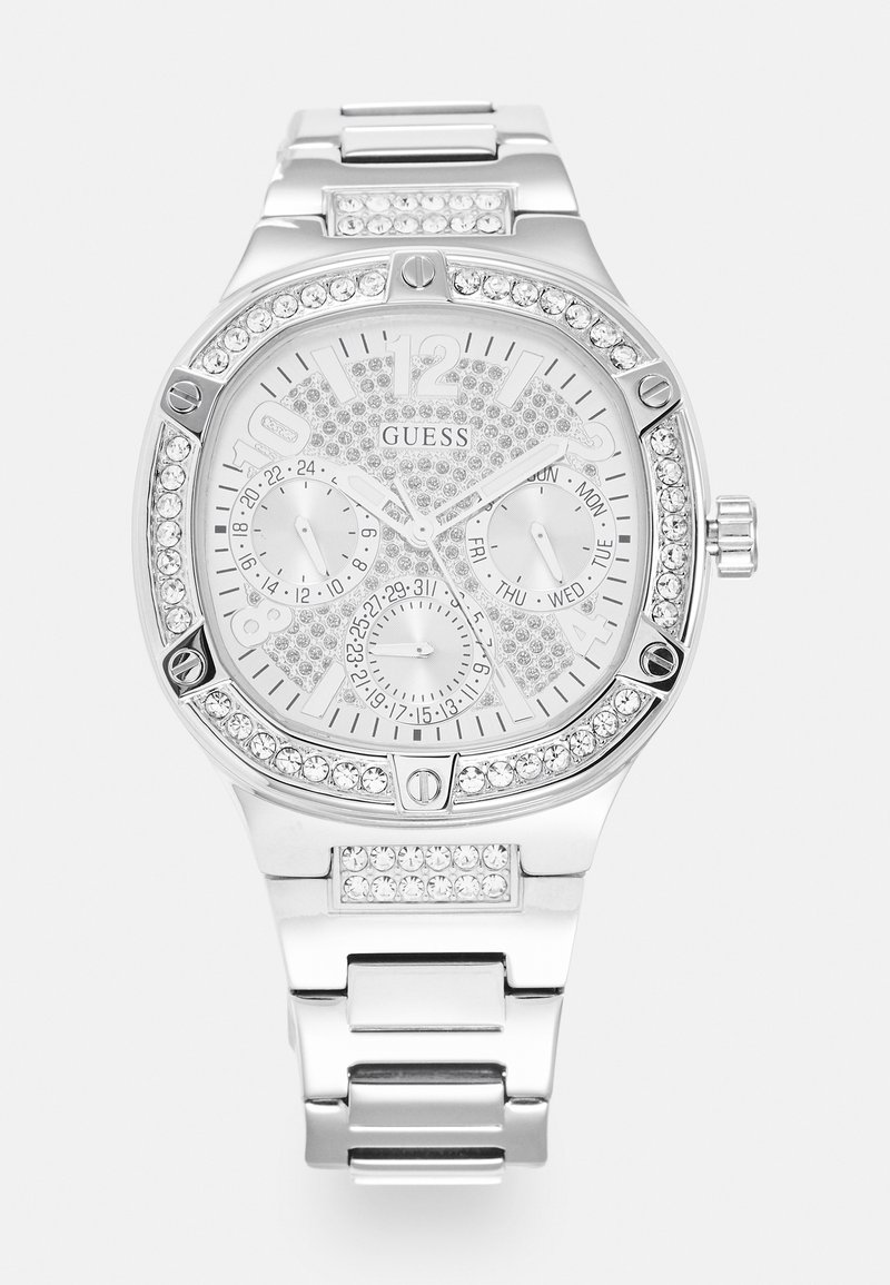 Montre-bracelet Guess argentée avec lunette en cristal et accents sur le bracelet, trois sous-cadrans affichant les fonctions 24 heures, jour et date.