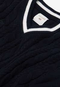 Jersey de punto con cable en color azul marino, con escote en V y ribete blanco. Hecho de un material suave, presenta patrones texturizados y una etiqueta cosida.