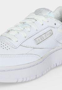 Hvid Reebok lædersneaker med snørebånd, polstret krave, perforeret tå og mærkelogo på siden og tungen.