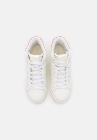 Sneakers alte bianche con tomaia in pelle liscia, punta tonda, lacci bianchi e un accento rosso sul collo. Dettaglio logo discreto visibile.
