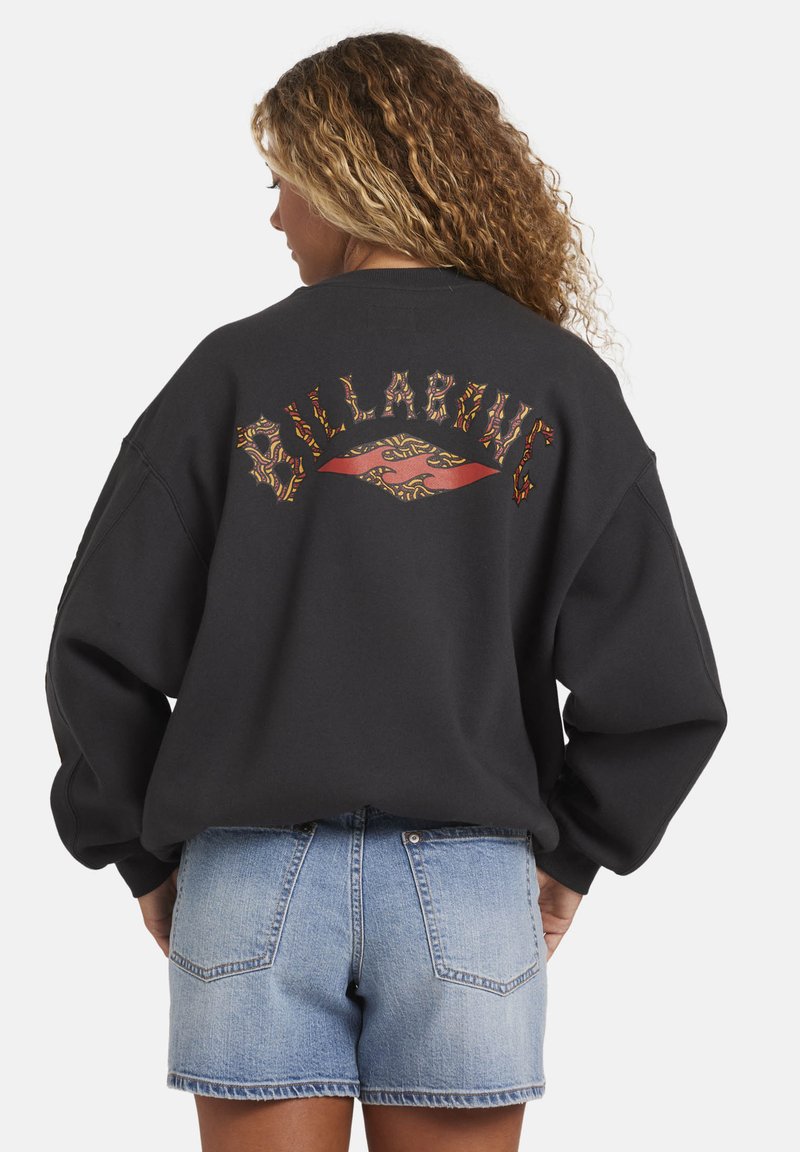 Sudadera negra de gran tamaño con el colorido texto "BILLABONG" y un gráfico en la parte trasera. Tela suave, hombros caídos y corte relajado.