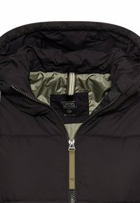 Black puffer jacket with a hood, featuring a green inner lining, side zip pockets, and a branded label. Zipper pull is metallic with an accent.