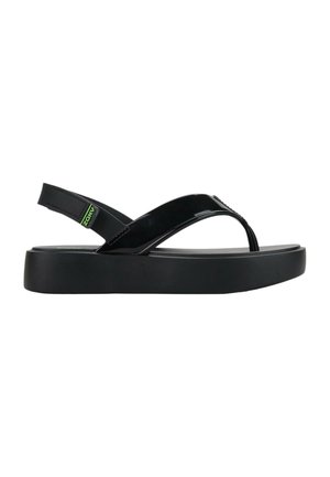 Sandalo platform nero con cinturino lucido tra le dita e cinturino posteriore regolabile con una piccola etichetta logo verde.