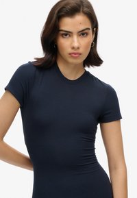 T-shirt ajusté à manches courtes de couleur marine, fabriqué en tissu lisse avec un col rond et des coutures subtiles, affichant une silhouette près du corps.