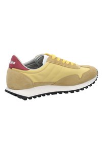 Sneaker in suede giallo e sabbia con lacci gialli, suola bianca, battistrada nero e linguetta rossa con testo logo bianco.