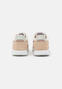 ASICS-sneakers med en kombination av mjuk beige mocka och mesh, ljus mintgrön accentfärg, samt en vit mellansula med ett texturerat yttre gummi.