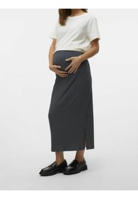 Jupe de maternité en tissu texturé gris foncé, dotée d'une fente sur le côté. Associée à une simple chemise blanche et des mocassins noirs.