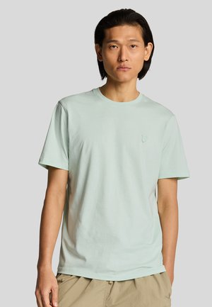 Lys grøn bomulds T-shirt med rund hals og korte ærmer, med en subtil logo detalje på brystet. Glat tekstur, afslappet pasform.