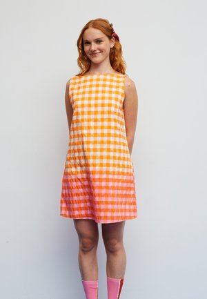 Sukienka w kratkę w odcieniach pomarańczy i różu, bez rękawów, wykonana z lekkiego materiału, o prostym kroju, z urokiem noszona.