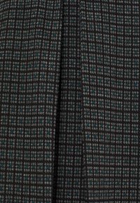 Tissu texturé présentant un motif de petits carreaux gris et teal sur fond noir; finition lisse avec un subtil éclat.