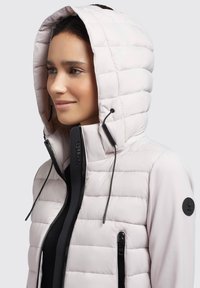Helles rosa, puffy Jacke mit Kapuze und schwarzen Akzenten, ausgestattet mit einem Reißverschluss vorne, seitlichen Taschen und gestepptem Design.