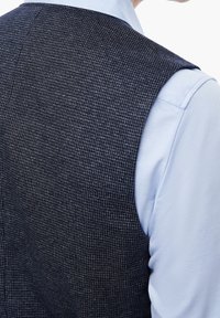 Marine-blauer geblümter Weste mit einem Hahnentritt-Muster, getragen über einem hellblauen Hemd. Verfügt über eine taillierte Passform und strukturierte Schultern.