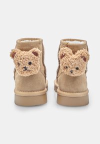Stivali alla caviglia in suede beige con morbidi accenti a forma di orso sul retro, dotati di una fodera interna soffice e suola piatta in gomma.
