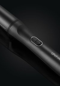 Bâton de coiffage noir avec une finition mate élégante et un bouton au centre. Présente des bords arrondis et un logo discret près de la base.