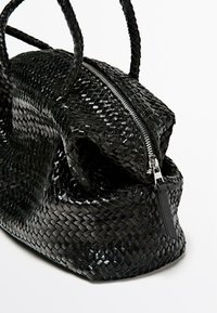Borsa a tracolla nera intrecciata con una finitura lucida, caratterizzata da materiale testurizzato, due manici e una chiusura con zip.
