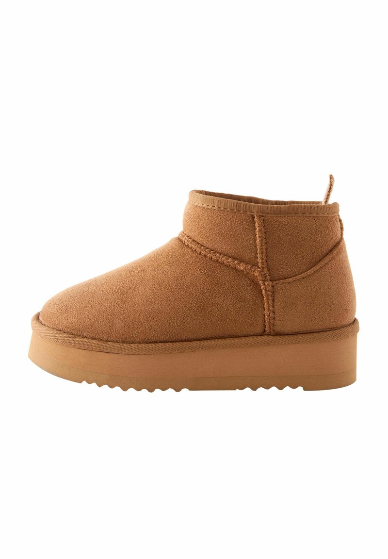 Tan ruskind ankle boot med rund tå, syede detaljer og en struktureret gummisål. Har en løkke bagpå for nemmere påtagning.