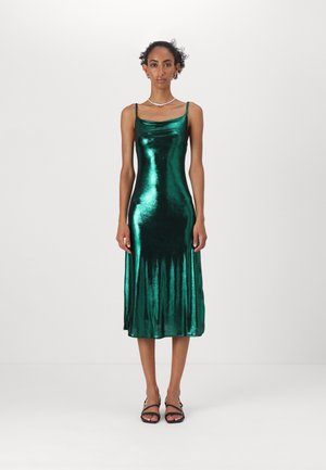 Robe midi métallique verte avec des bretelles fines, décolleté en cowl, et une texture lisse et brillante. Ourlet évasé et silhouette élégante.