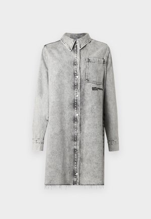 Abito camicia in denim grigio chiaro con chiusura a bottoni, colletto, maniche lunghe e taschino sul petto con ricamo del logo nero. Orlo sfilacciato.