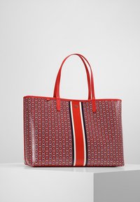 Czerwona torba na ramię z trwałego materiału, zdobiona plecionym wzorem. Posiada długie czerwone rączki oraz centralny pasek w kolorach czerwonym, białym i niebieskim.