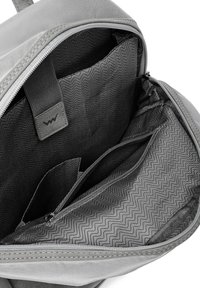 Der Innenraum des grauen Stoff-Rucksacks bietet eine Zickzackmuster-Fütterung, mehrere Taschen und einen robusten Reißverschlussverschluss mit einem strukturierten Tab.