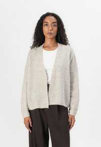 Light beige knitted cardigan with a relaxed fit, open front, and long sleeves. Soft texture, ribbed edges, and a slightly cropped length.