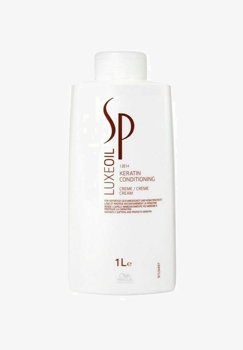 Hvid plastikflaske med flip-top låg. Etiketten viser rød tekst med "SP LUXEOIL" og "KERATIN CONDITIONING" vist tydeligt. 1L volumen.