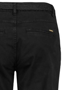Zwarte broek met een geweven zwarte riem. Soepele stof, twee achterzakken en een kleine gouden accent nabij een zak.
