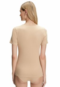 Beżowa koszula z krótkim rękawem i okrągłym dekoltem, wykonana z gładkiego materiału, charakteryzująca się dopasowanym krojem i minimalnymi detalami przeszycia.