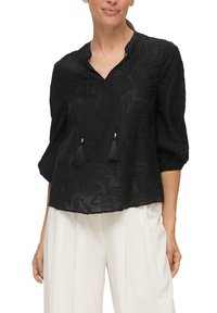 Blusa negra con patrón floral texturizado, escote en V y lazos ajustables con borlas. Tiene mangas de 3/4 y un corte relajado.