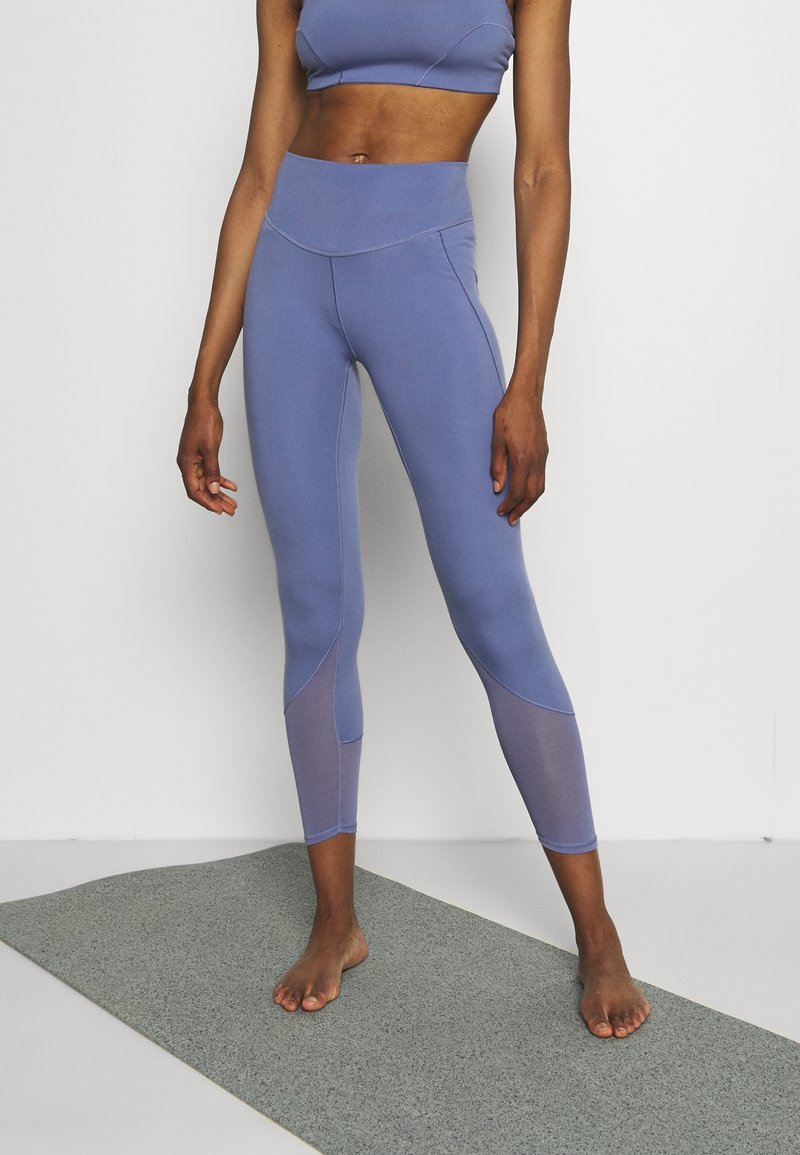 Leggings viola chiaro con un design aderente, caratterizzati da pannelli in rete lungo i lati, realizzati in un tessuto liscio e elastico.