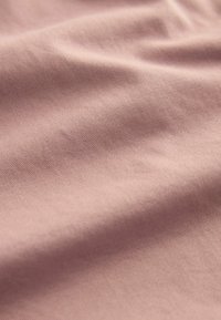 Tissu doux de couleur mauve clair avec une texture fine côtelée diagonale et des plis doux créant des ombres et des éclairages subtils.