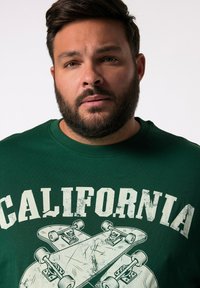 Groene sweatshirt met een grote grafische afbeelding met het woord "CALIFORNIA" en twee skateboardontwerpen. Katoenen materiaal, ronde hals, ontspannen pasvorm.