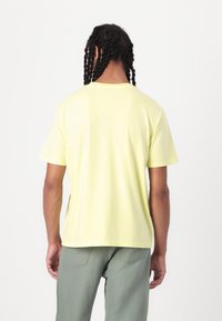 Yellow cotton t-shirt with short sleeves, round neckline, and a relaxed fit. The fabric appears soft with a slight sheen.