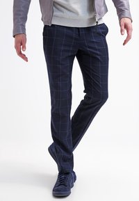Navy blue pants with a grid pattern, made from soft fabric. The design features elastic waistband, slim fit, and a subtle sheen.