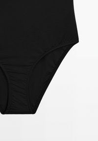 Svart baddräktbottom tillverkad av slätt tyg, med högskurna ben och sydda sömmar för hållbarhet.
