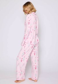 Conjunto de pijama rosa con un patrón de cascanueces y corazones. Hecho de tela suave, con mangas largas y pantalones holgados, puños simples en los tobillos.