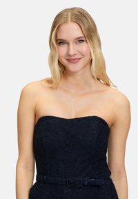 Robe en dentelle marine sans bretelles avec un motif floral et un corsage ajusté, dotée d'une large ceinture à la taille. Tissu lisse et texturé.