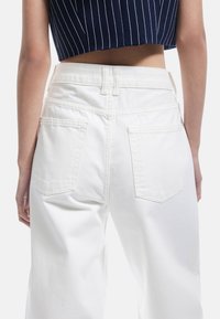 Witte high-waisted jeans met een recht model, achterzakken en subtiele stiksels, gezien vanuit de achterkant.