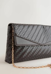 Fekete szövött bőr alkalmi táska arany láncpánttal, világos felületen fekve, háromszög alakú fedélzárral.