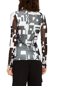 Langermige top met een geometrisch zwart-wit patroon, voorzien van semi-doorzichtige zwarte meshstof op de mouwen. Gladde afwerking.