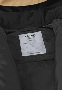 Schwarze, wetterfeste Kinderjacke mit Innenfutter und einem beige farbenen Kragen. Enthält ein Pflegeetikett mit "reima", Größe 104/4T, und Anweisungen zum Weitergeben.