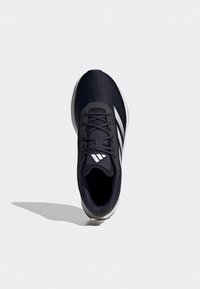 Scarpa sportiva nera con una tomaia in rete testurizzata, con dettagli bianchi e un sistema di allacciatura. Design leggero con una suola ammortizzata.