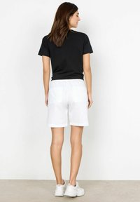 Black short-sleeve t-shirt with a round neckline, paired with white shorts featuring an elastic waistband and two back pockets.