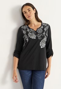 Sort top med trekvart ærmer, prydet med hvid paisley broderi. V-hals design, blødt stof med opprullede ærmekanter.