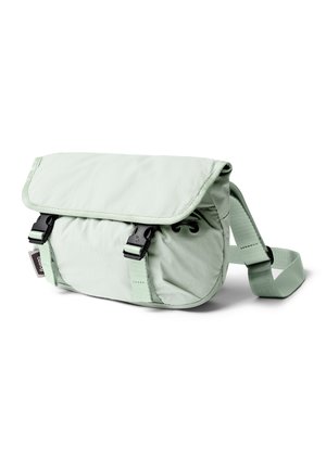 Sac bandoulière vert clair avec sangle ajustable, rabat avant sécurisé par deux boucles en plastique noir, et une petite étiquette de marque sur le côté.