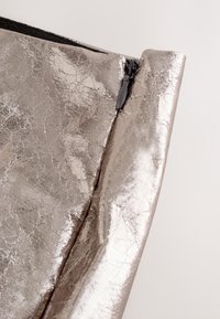 Busta argentata metallica con una texture rugosa, caratterizzata da una cerniera nera in alto, che presenta un design elegante e minimalista.