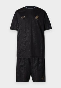 Melns sporta kostīms no viegla auduma. Dizainā ir ģeometrisks raksts, īsas piedurknes un zelta krāsas logotips. Apaļa kakla izgriezuma dizains.